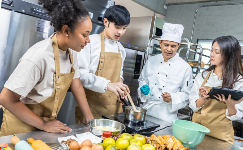 Career and Technical Education culinary students collaborate with their instructor during a hands-on classroom lesson.